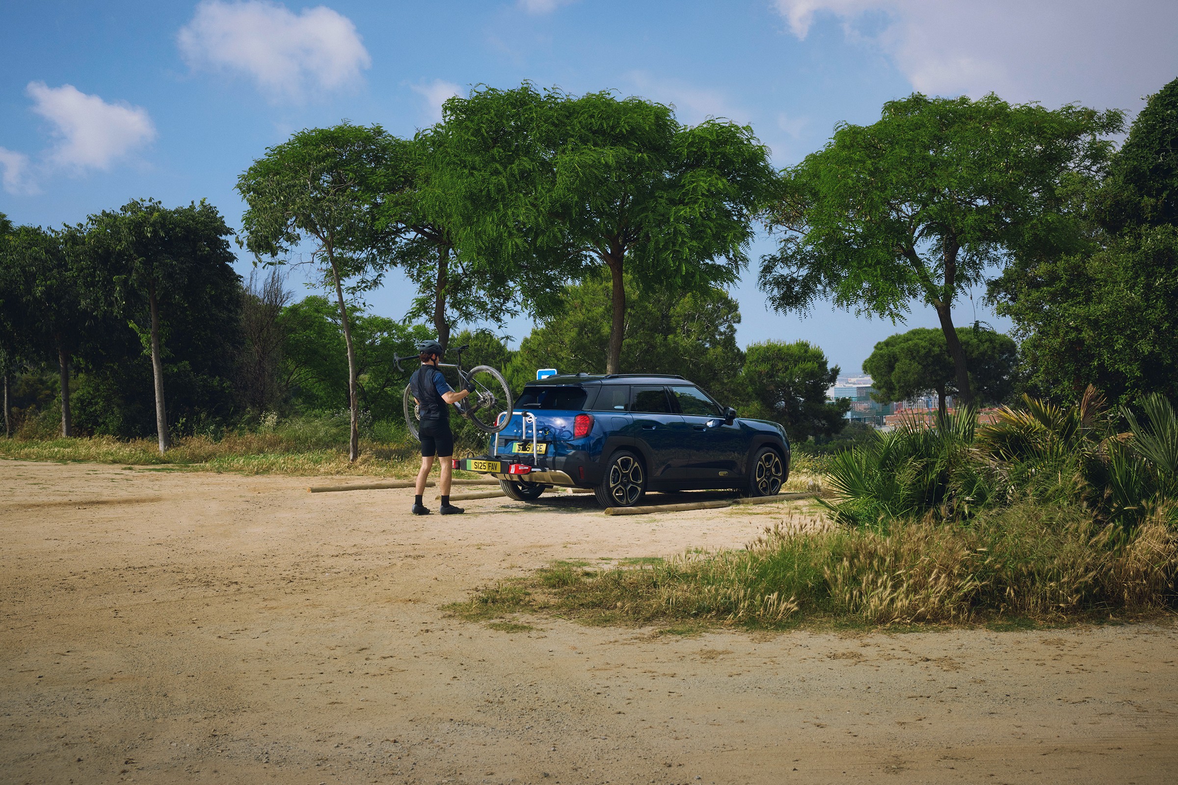 Ciclista a retirar uma bicicleta do suporte traseiro de um Mini Aceman Elétrico,  rodeado por natureza